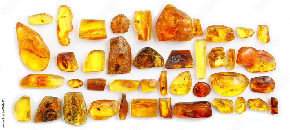 Panoramic shot of many pieces of amber with inclusions on a white background. Pieces of sunstone polished with different inclusions. Insects and larvae in frozen ancient resin. Color resin. Panorama