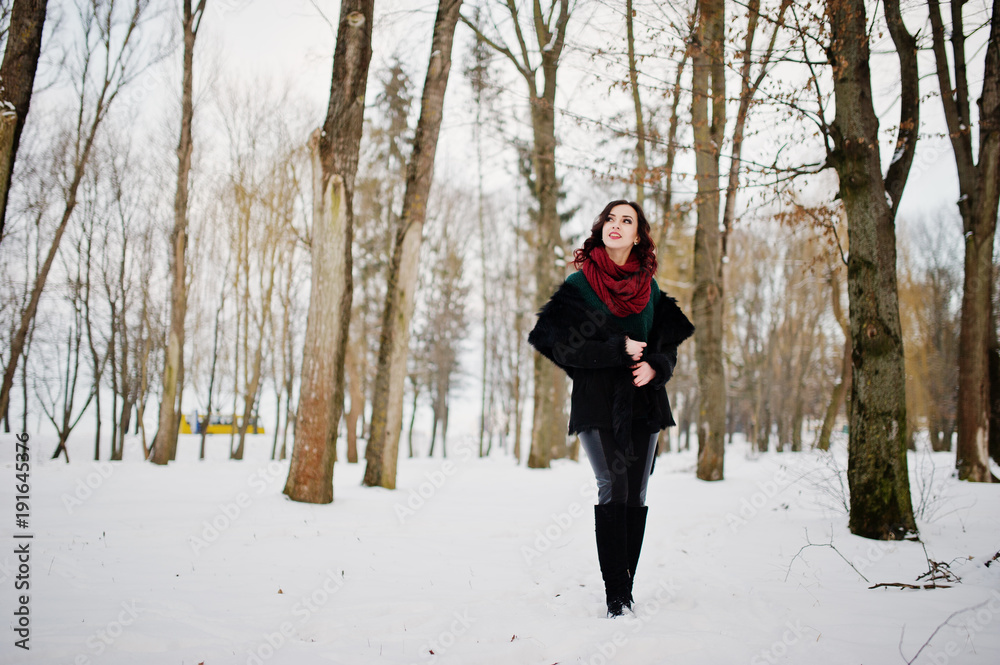 Brunette girl in green sweater, coat and red scarf outdoor on evening winter day.