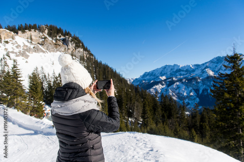 Junge attraktive Frau macht Fotos mit Smartphone im Schnee