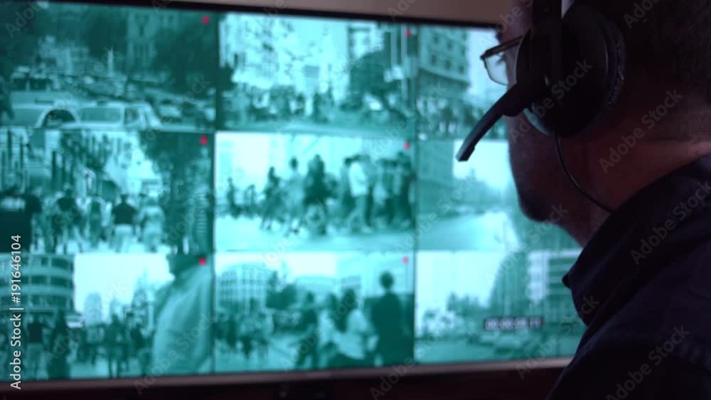 Security officer watching monitoring displays in control room. Security