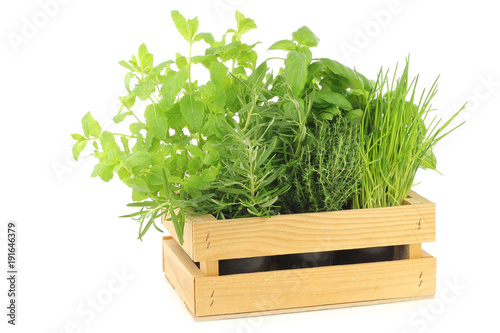mixed herbs in a wooden crate on a white background