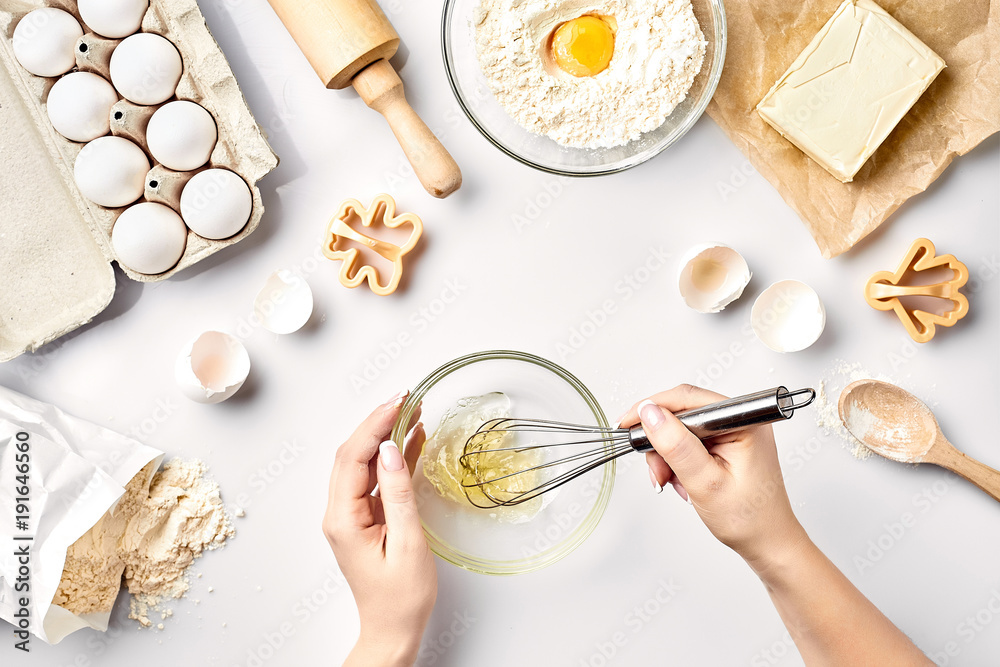 Female chef whisking eggs in glass bowl on kitchen table Female chef whisking eggs in glass bowl on kitchen table