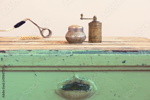 Old Turkish manual grinder, immersion heater and wheat on a wooden table