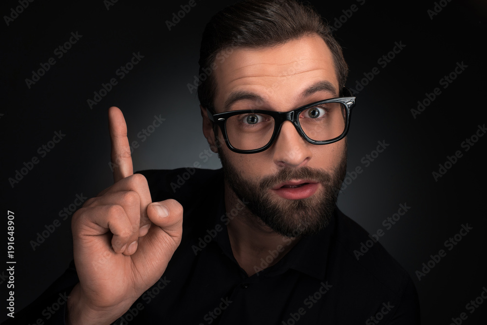 portrait of man in eyeglasses pointing up isolated on black portrait of man in eyeglasses pointing up isolated on black