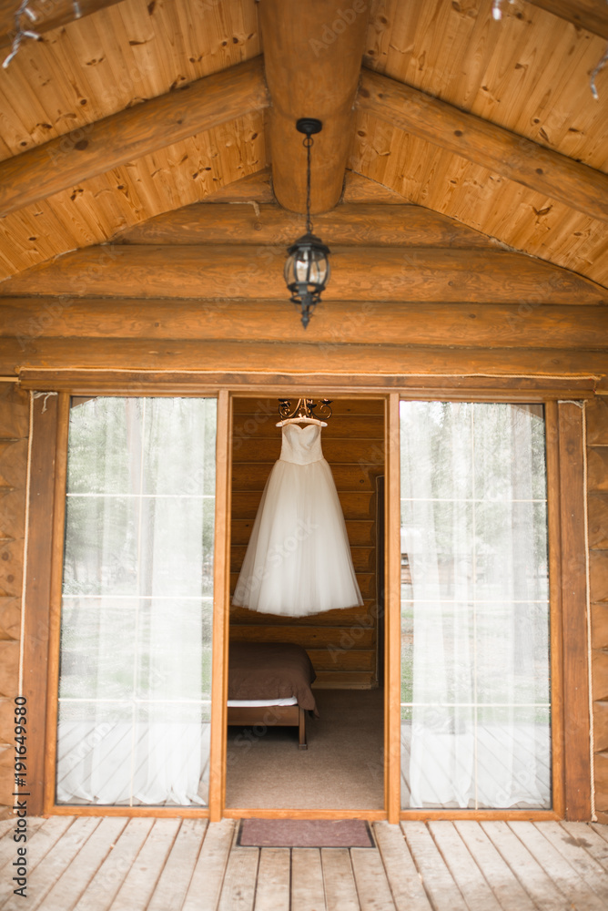 White lush wedding dress hanging on the hanger in the room view from the street. Bridal gown.