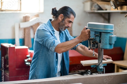 Carpenter using machinery in workshop photo