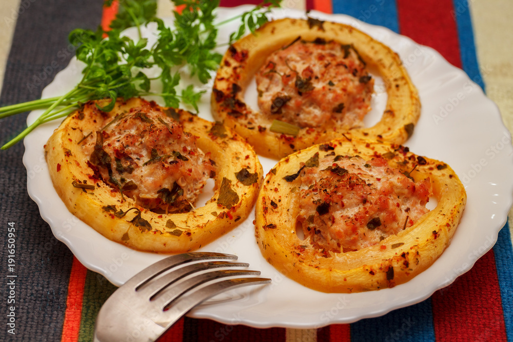 Baked slices of courgettes, stuffed with minced meat from turkey, on a white plate. Striped tissue napkin on the table. Baked slices of courgettes, stuffed with minced meat from turkey, on a white plate. Striped tissue napkin on the table.