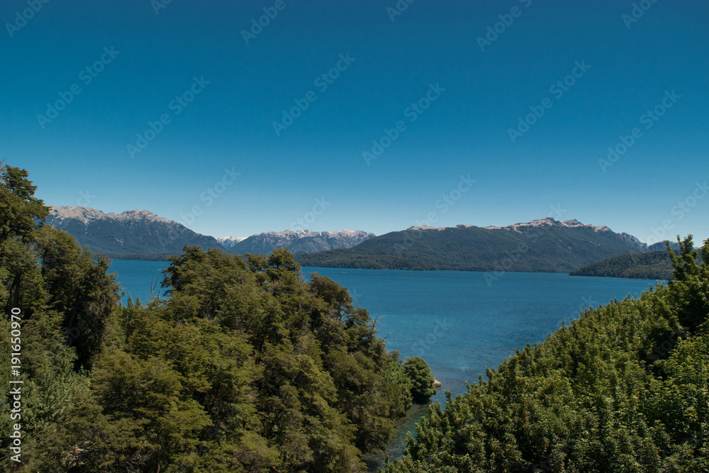 Landscape of a turquoise lake with mountains and groves
