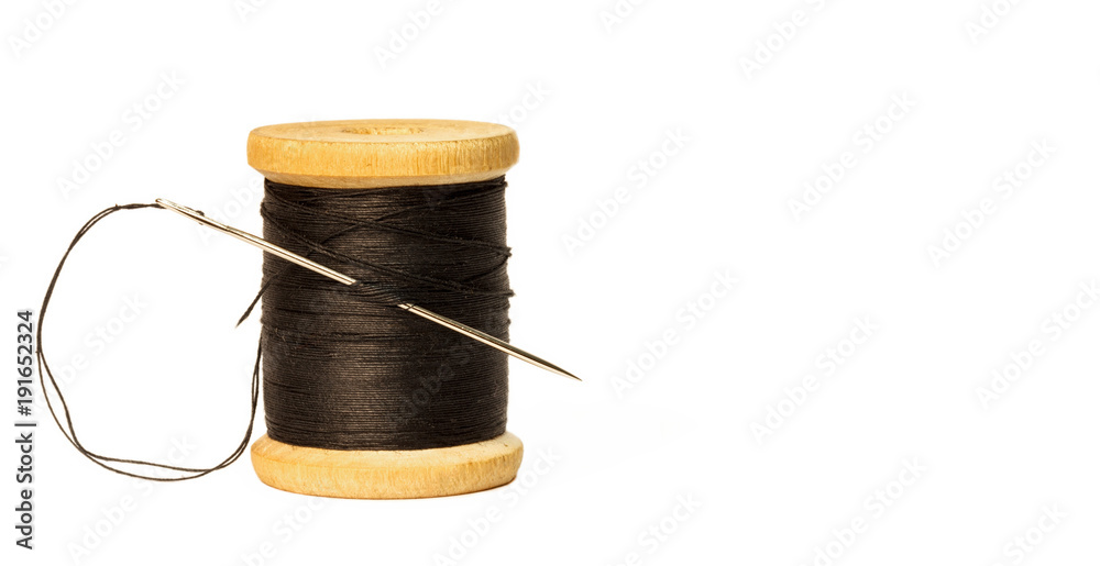 sewing needle with black thread stuck in wooden spool with black threads  close up isolated on white background Stock Photo