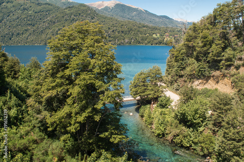 Landscape of a turquoise river rising from a lake and mountains in the background