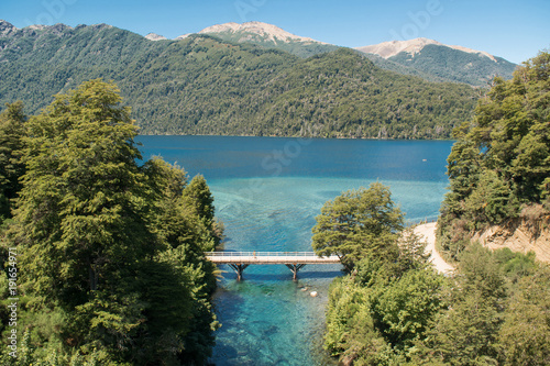 Landscape of a turquoise river rising from a lake and mountains in the background