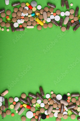 Set of colorful pills scattered on green background photo