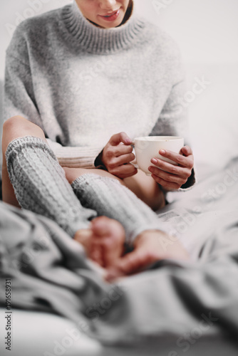 Woman drinking coffee while sitting on the bed in the morning. photo