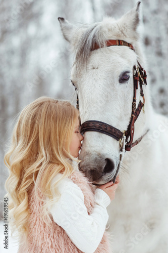 Little blonde girl with a white horse