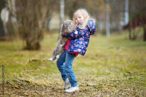 Cute little girl with her pet cat on chilly autumn day