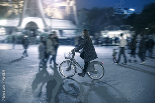 Happy young attractive woman riding her bicycle on a street in front of the Eiffel Tower © tannujannu