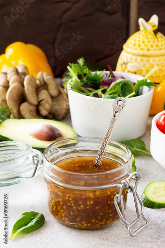 Superfoods and homemade salad dressing vinaigrette with mustard, honey, balsamic vinegar and olive oil on a stone or slate background. Copy space. photo