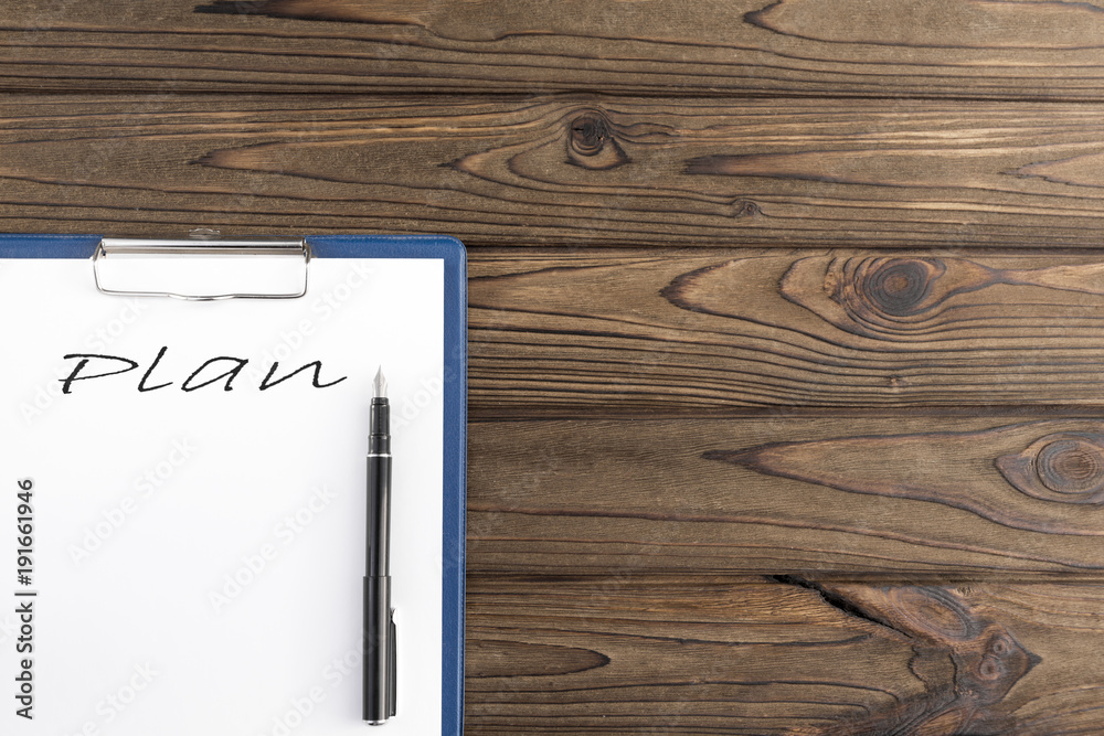 the plan is written on a piece of paper with a fountain pen. on a wooden background.