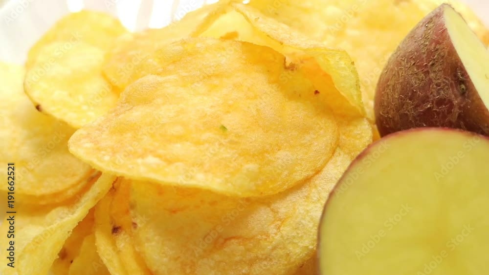 Homemade potato chips. Fast food. Popular junk food. Potato tubers and chips rotate smoothly on bamboo napkin. Diabetic diet. Homemade potato chips. Fast food. Popular junk food. Potato tubers and chips rotate smoothly on bamboo napkin. Diabetic diet.