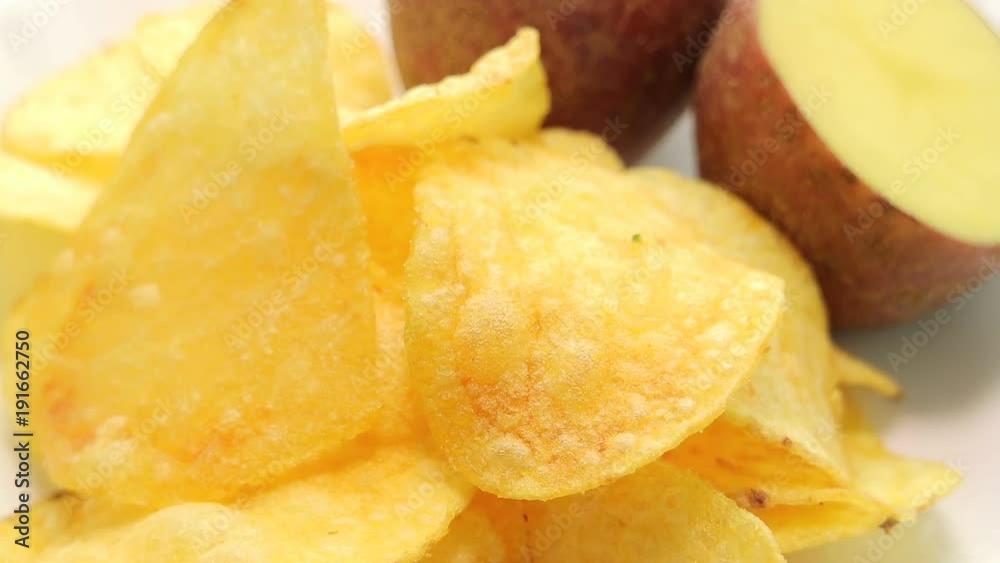 Homemade potato chips. Fast food. Popular junk food. Potato tubers and chips rotate smoothly on bamboo napkin. Diabetic diet. Homemade potato chips. Fast food. Popular junk food. Potato tubers and chips rotate smoothly on bamboo napkin. Diabetic diet.