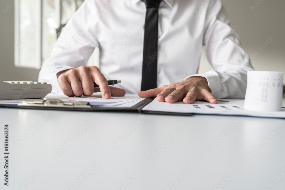Low angle view of a businessman pointing to an analytical graph Low angle view of a businessman pointing to an analytical graph