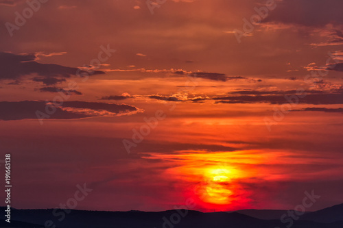 Cloudy colorful sunset with a big sun over the hills, Enisala, Dobrogea, Romania © mihaelastancu