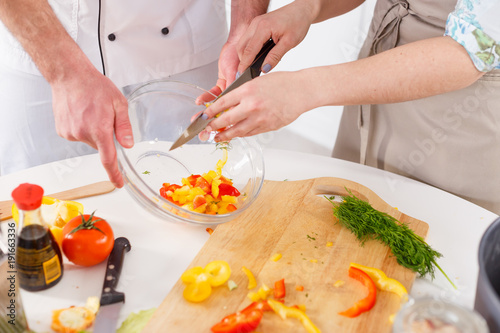A woman is preparing a salad led by a professional chef.