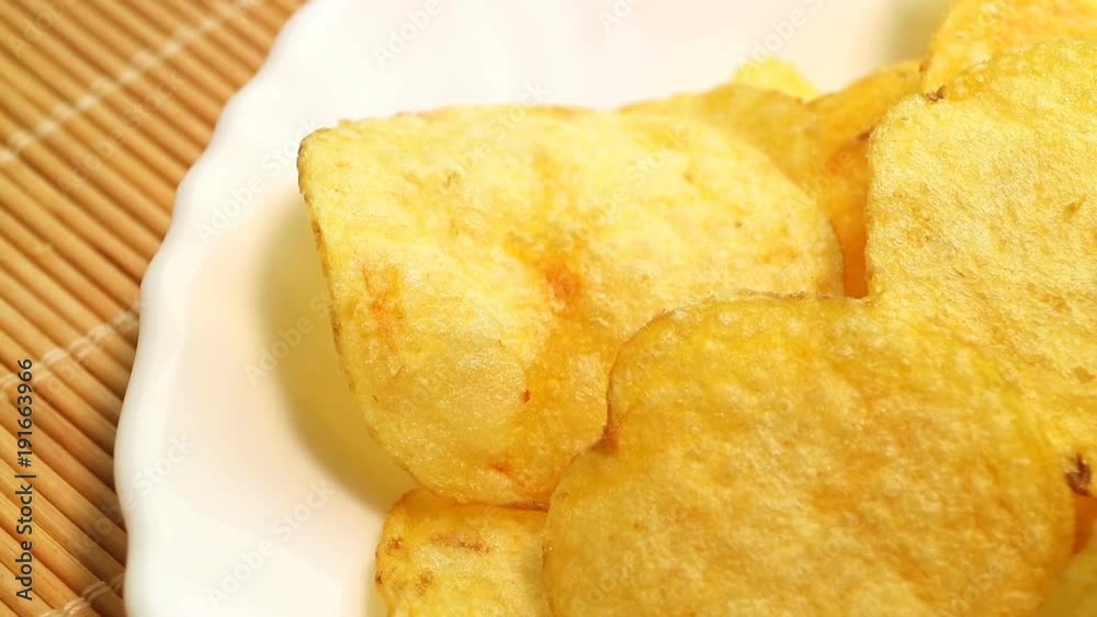 Homemade potato chips. Fast food. Popular junk food. Potato tubers and chips rotate smoothly on bamboo napkin. Diabetic diet. Homemade potato chips. Fast food. Popular junk food. Potato tubers and chips rotate smoothly on bamboo napkin. Diabetic diet.