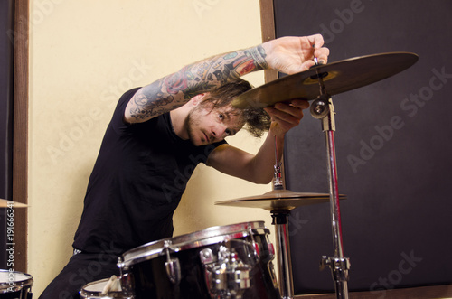 Photo Tattooed drummer adjusting cymbal