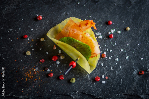 isolated shrimp appetizer with mint leaf and radish on black plate 