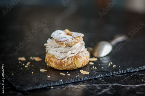 Obraz na płótnie Paris Brest french cream cake pastry isolated on black plate sprinkled with almonds w salonie