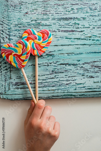 Two colored striped rainbow candy on a stick in the form of a heart. on a blue old vintage wooden background. The concept for Valentine's Day. photo