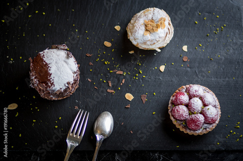 Obraz na płótnie assorted desserts on black plate raspberry tart cream cake paris brest and chocolate cake w salonie