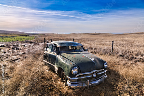Abandoned antique car in field.