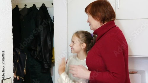 Happy young mother leaving daughter with grandma at home, saying goodbye photo