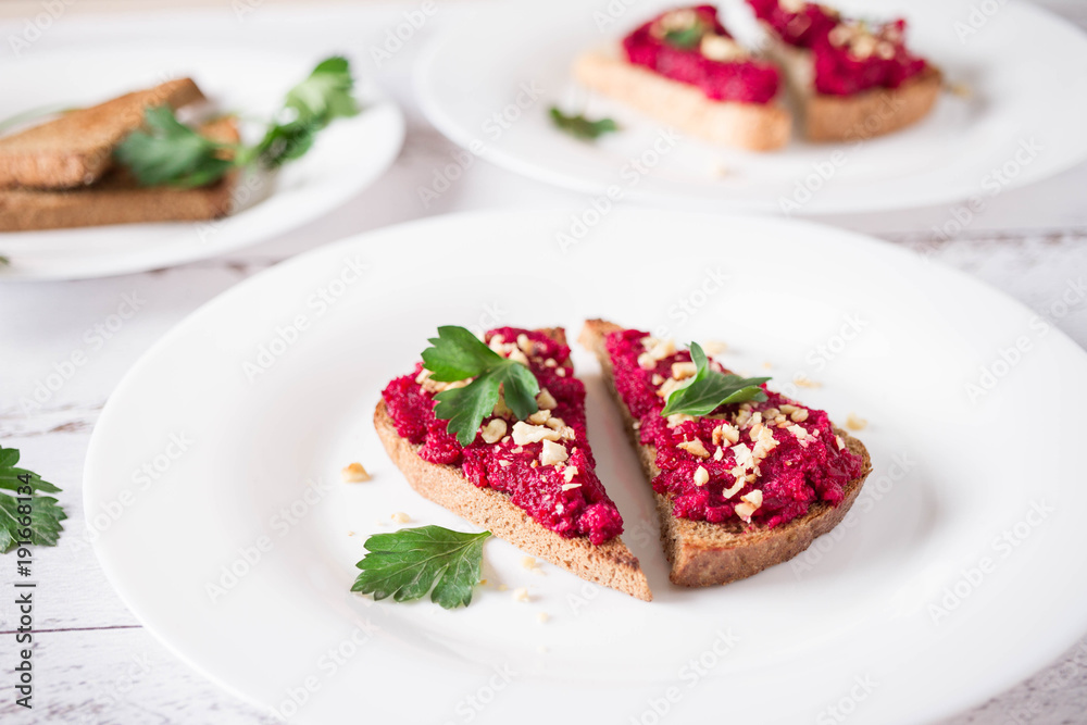 Homemade toast from whole grain bread with beet paste, greens and nuts. Useful dietary baking. Beet hummus. Healthy food for vegan Homemade toast from whole grain bread with beet paste, greens and nuts. Useful dietary baking. Beet hummus. Healthy food for vegan