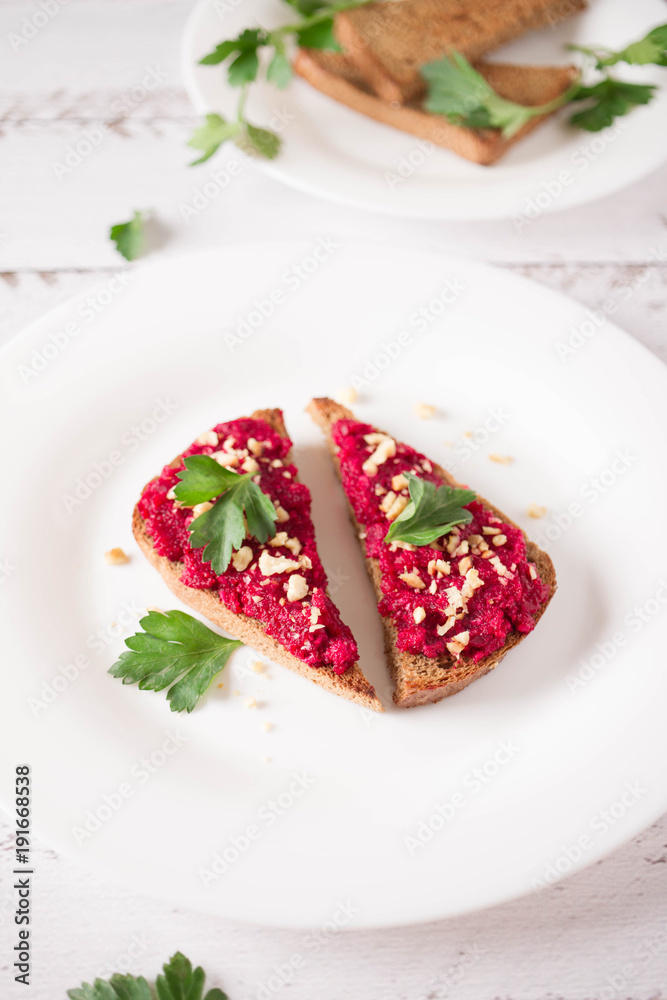 Homemade toast from whole grain bread with beet paste, greens and nuts. Useful dietary baking. Beet hummus. Healthy food for vegan Homemade toast from whole grain bread with beet paste, greens and nuts. Useful dietary baking. Beet hummus. Healthy food for vegan