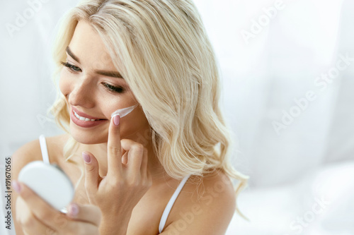 Beauty Face Care. Woman Applying Cream On Skin.