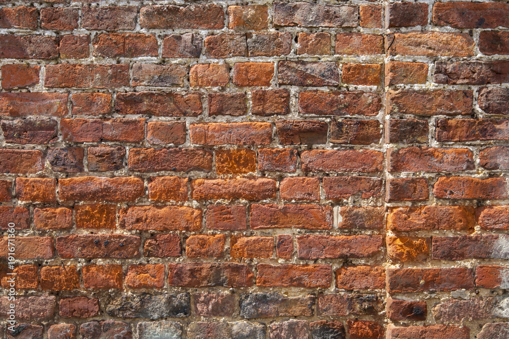 Obraz premium An old weathered, damaged, badly repaired red brick wall full frame