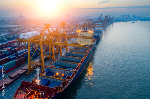 Containers yard in port congestion with ship vessels are loading and discharging operations of the transportation in international port.Shot from drone.