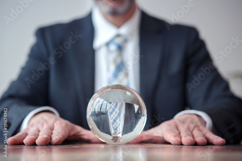 businessman looking at glass ball on table