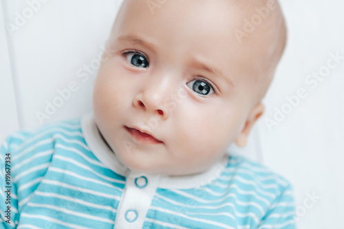 The kid looks beautifully with mysterious eyes on a light background