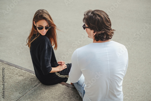 Shy girl sitting on a wall with boyfriend and smiling © sasamihajlovic