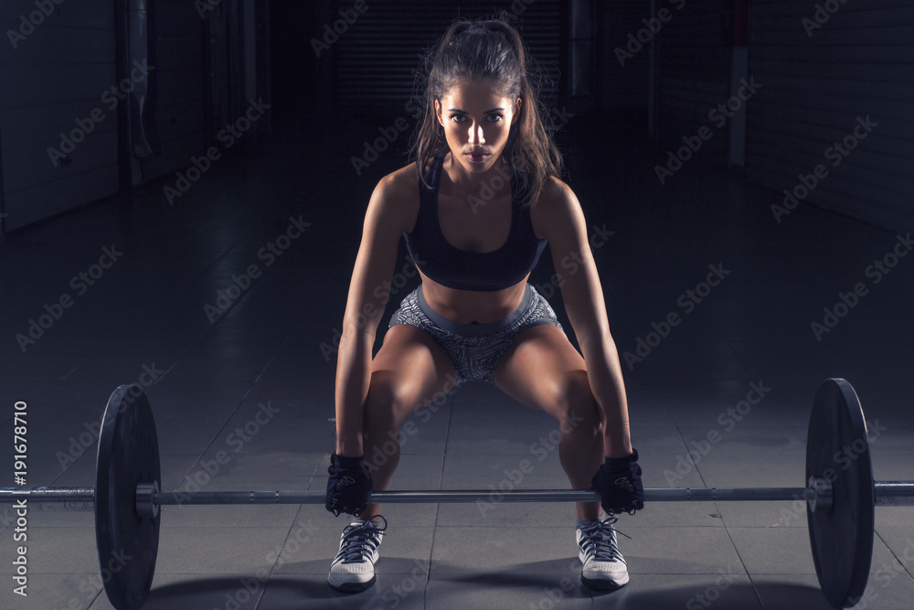 Beautiful long dark hair girl with weight on hands exercise on gym Beautiful long dark hair girl with weight on hands exercise on gym