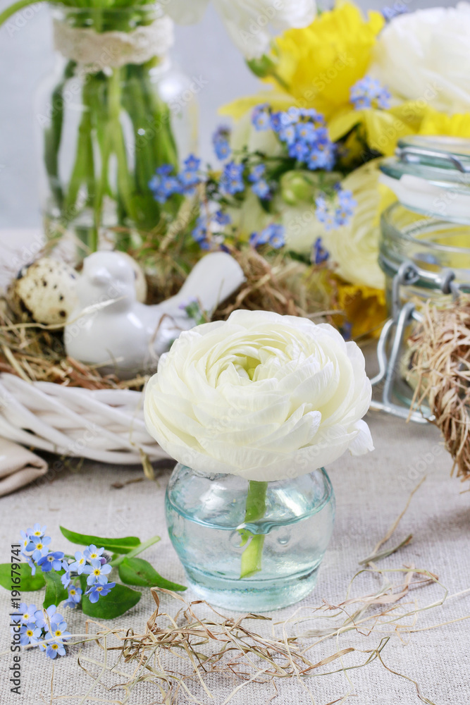 Easter table rustic decorations with white ranunculus flower, hay and wicker wreath.