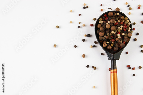 Wooden spoon with peppercorns on white