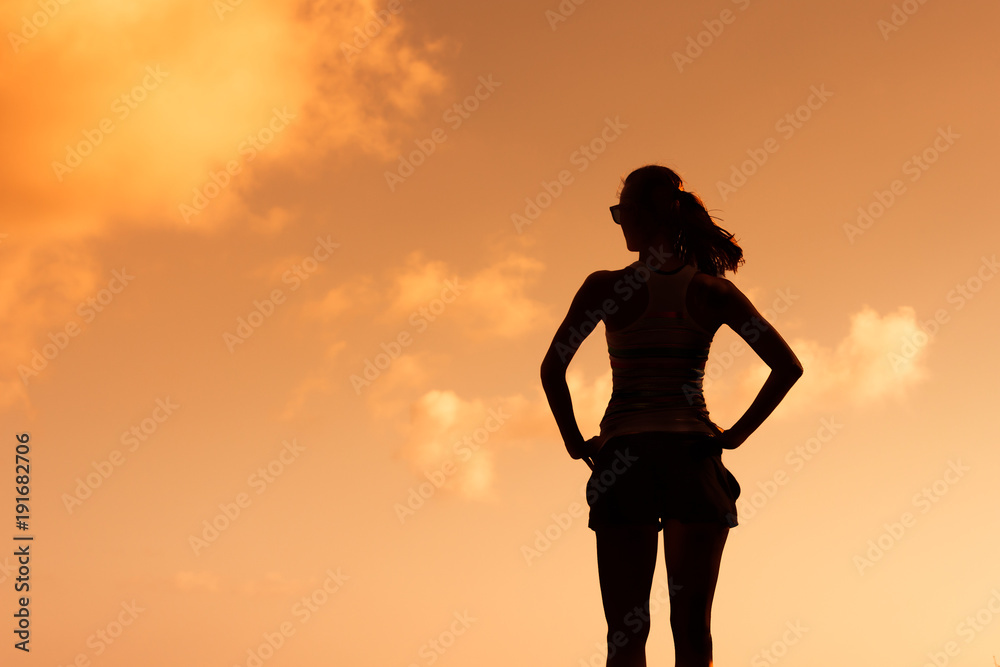 Silhouette of woman standing in the sunset. 