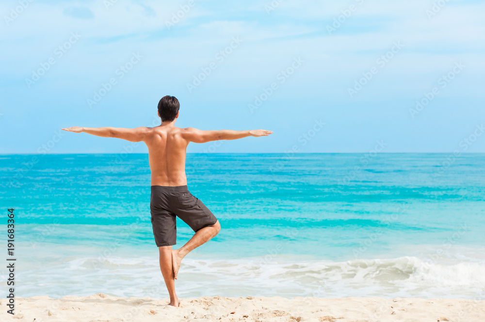 Male yoga stretch on the beach. 