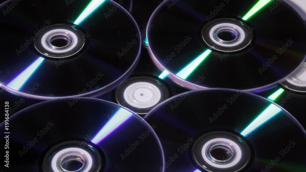 A bunch of shiny DVDs rotating. Dark shot.
A bunch of shiny DVDs rotating. Dark shot.