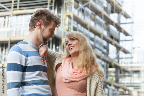 Couple with keys on front of new modern house